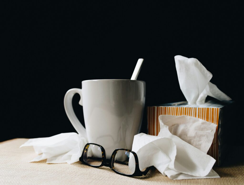 Image of cold and illness related items like tissues, a mug, and glasses.