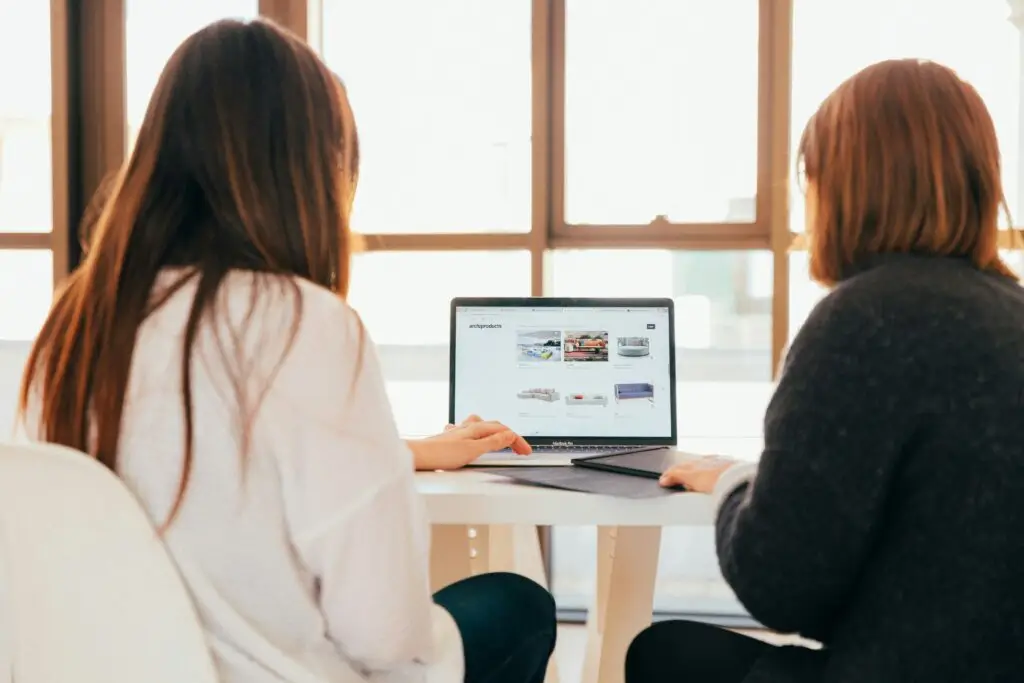 Two women working together on a laptop, showing what the job of a Deployment Coordinator could look like.